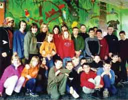 Die Klasse steht vor einem selbst gemalten Wandbild mit Regenwaldmotiven.