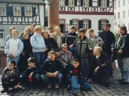 Kinder und ältere Menschen stehen gemeinsam vor Fachwerkhäusern in der Altstadt.