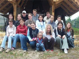 Die Austauschgruppe sitzt und steht unter einem hölzernen Unterstand.