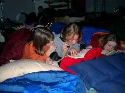 Kinder liegen bei der Lesenacht in Schlafsäcken und lesen.
