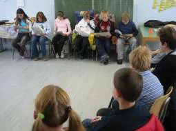 Kinder sitzen im Stuhlkreis und lesen einander vor.