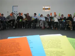 Lehrkräfte sitzen im Kreis, im Vordergrund liegen bunte Moderationskarten.