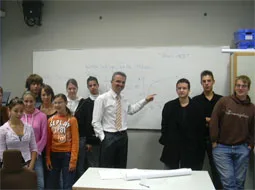Eine Gruppe steht mit dem Referenten vor dem Whiteboard im Klassenraum.
