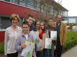 Die Ausgezeichneten halten ihre Urkunden vor dem Schulgebäude in die Kamera.