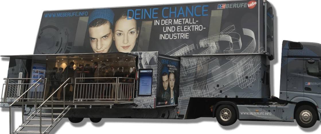 Ein großer Info-Truck der Metall- und Elektro-Industrie mit der Aufschrift „Deine Chance in der Metall- und Elektro-Industrie“ und „www.meberufe.info“; der aufklappbare Anhänger bildet einen begehbaren Ausstellungsbereich mit Treppe, Glasfront und Bildschirmen.