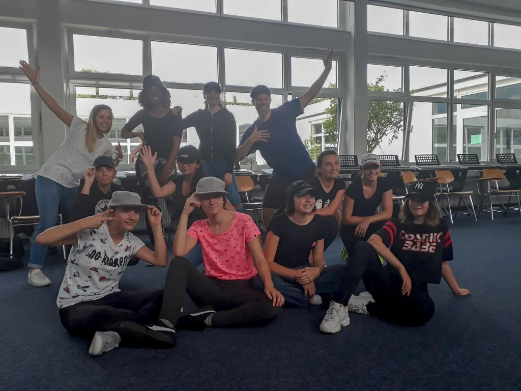 Gruppe sitzt und steht für ein Foto im Aufenthaltsraum.