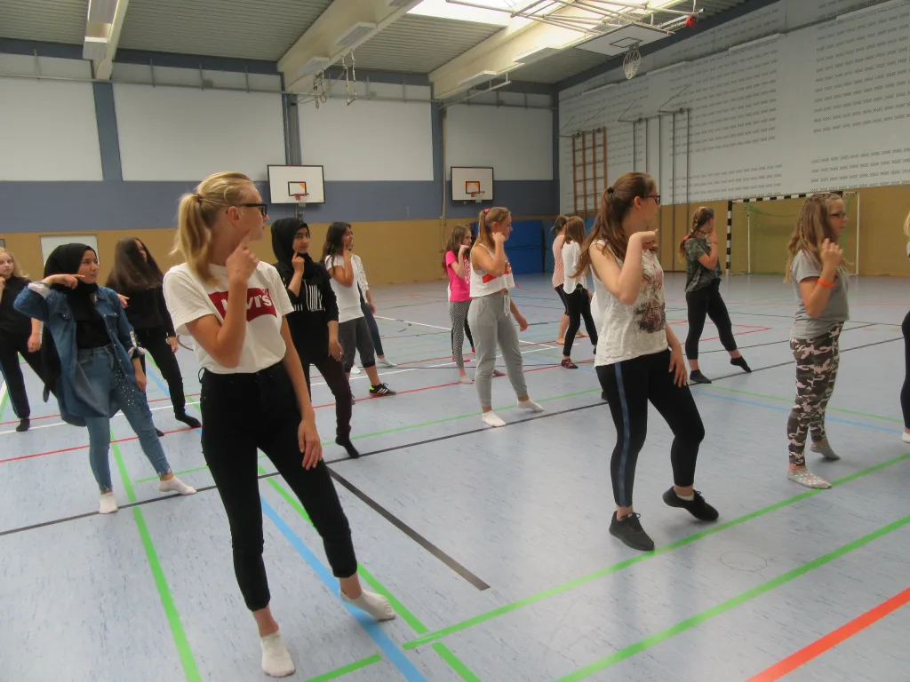 Jugendliche tanzen in der Sporthalle.