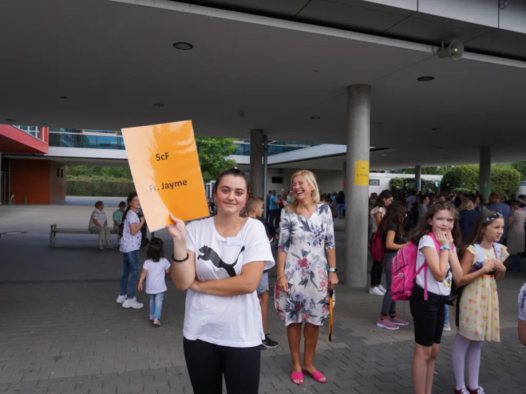 Zwei Personen halten ein oranges Klassenschild hoch.