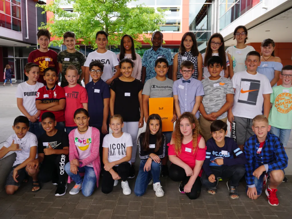Klassenfoto einer neuen fünften Klasse unter den Bäumen.