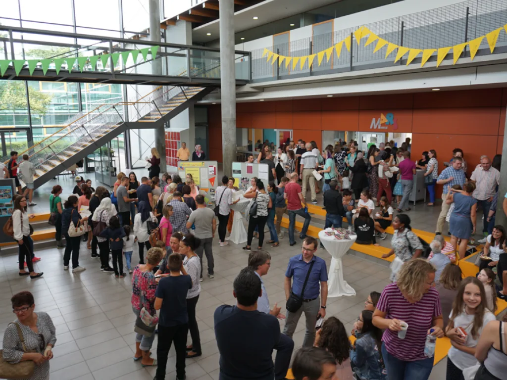Belebtes Foyer mit Wimpelketten und vielen Gästen.