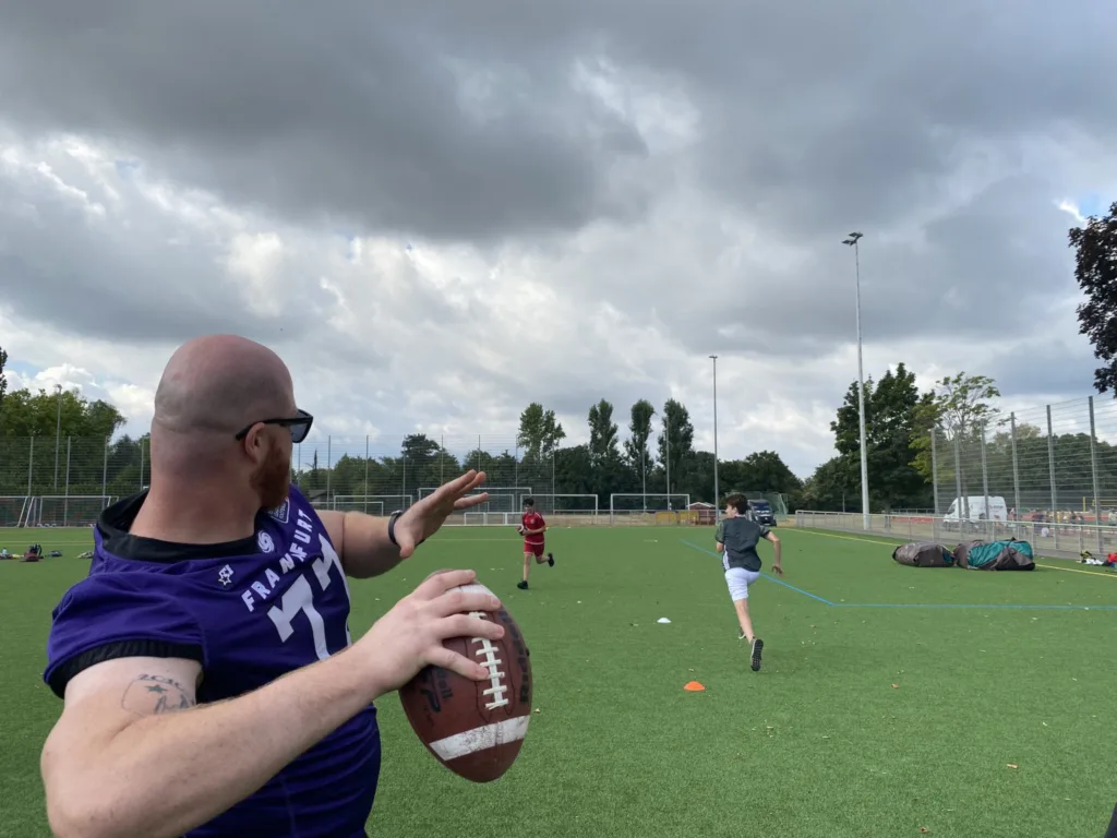 Ein Footballspieler der Frankfurt Galaxy im lila Trikot holt auf dem Sportplatz mit dem Ball zum Wurf aus.