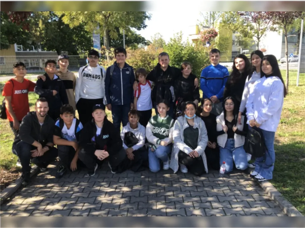 Eine große Gruppe Jugendlicher stellt sich im Freien für ein Gruppenfoto auf.