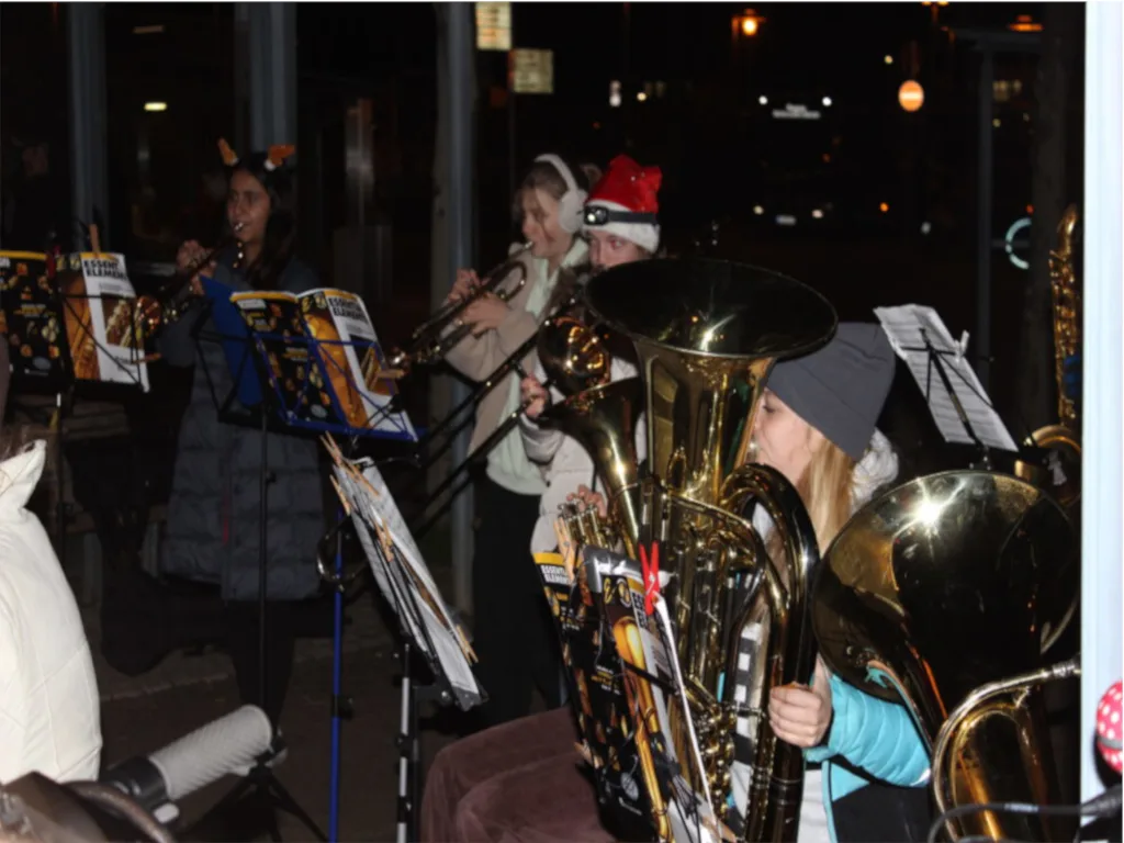 Die Bläserklasse spielt am Abend am Langener Bahnhof, im Vordergrund eine Tuba und beleuchtete Notenständer.