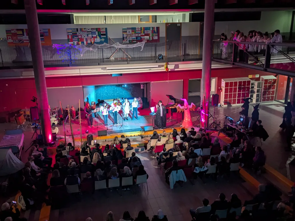 Die Pausenhalle ist rot ausgeleuchtet und mit Publikum gefüllt.