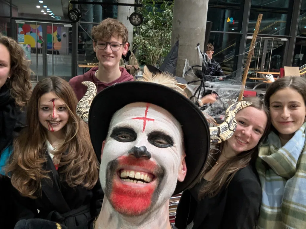 Vier Jugendliche stehen neben einer als Clown geschminkten Person.