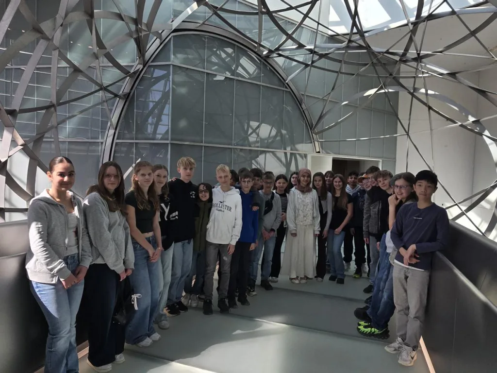 Die Gruppe steht unter dem gläsernen Dach der Halle für ein Gruppenfoto.