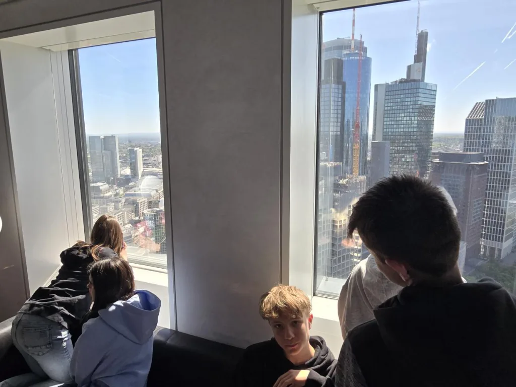 Jugendliche blicken aus dem Fenster auf die Frankfurter Skyline.