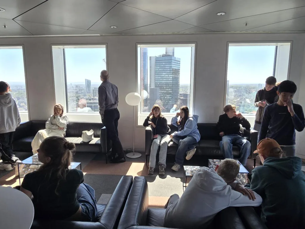 Jugendliche sitzen in einem Aufenthaltsraum mit Panoramafenstern.