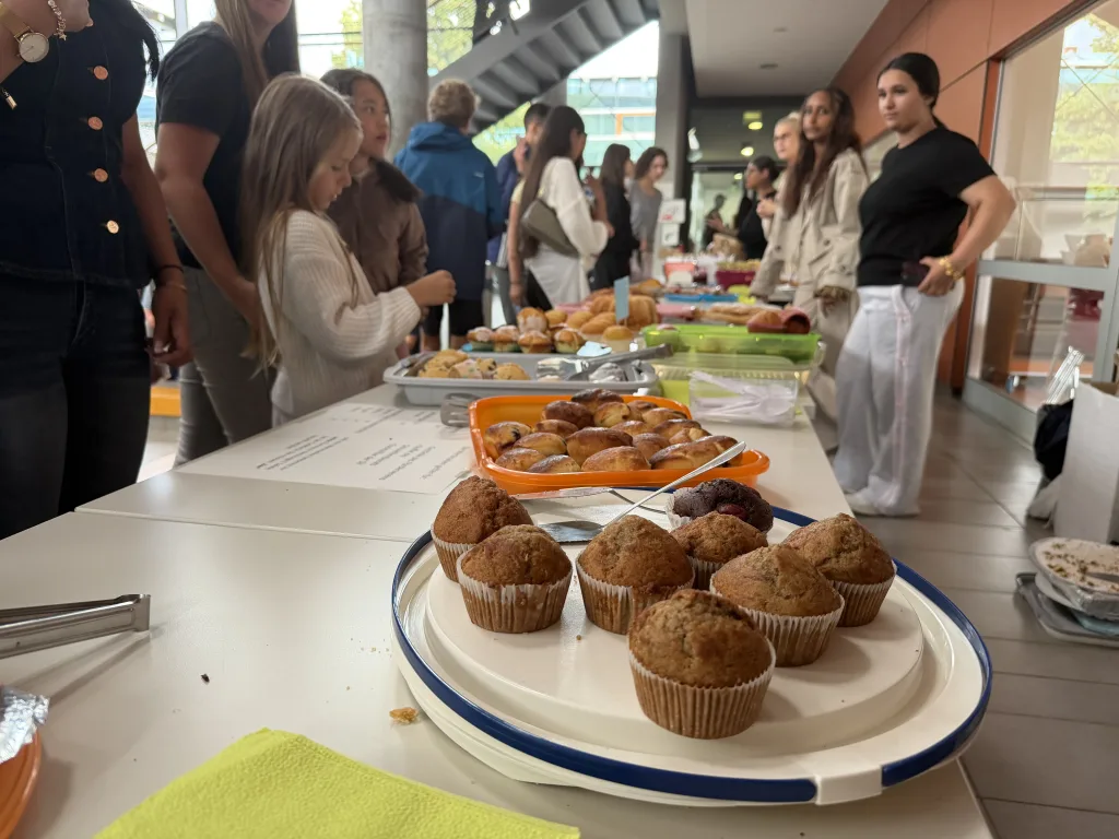 Auf einem Tisch stehen Teller mit Muffins und Gebäck für den Verkauf.