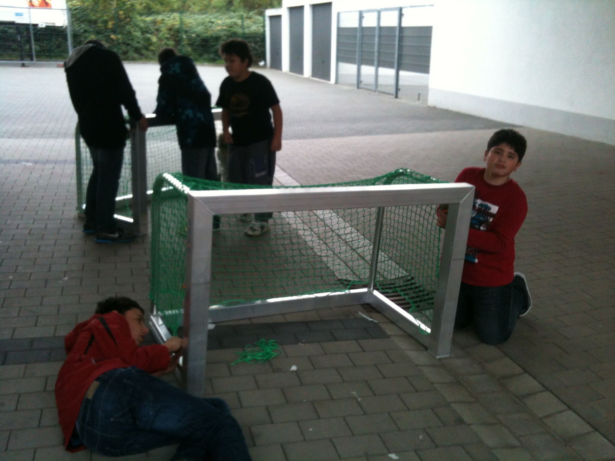 Man sieht Kinder die ein Tor Aufbauen.