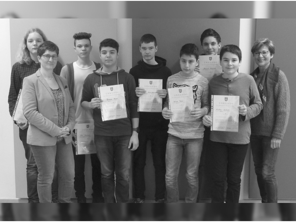 Schüler und Schülerinnen halten eine Urkunde in die Kamera