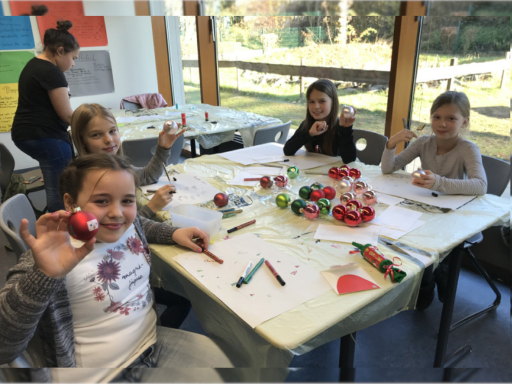 Schüler/-innen sitzen am Tisch und präsentieren stolz ihre selbstgebastelten Werke