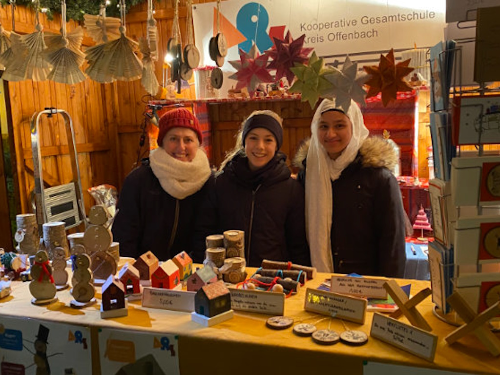 Frau Dahmer (links) gemeinsam mit zwei engagierten Schülerinnen während ihrer Schicht in der ARS-Hütte auf dem Weihnachtsmarkt in Langen.